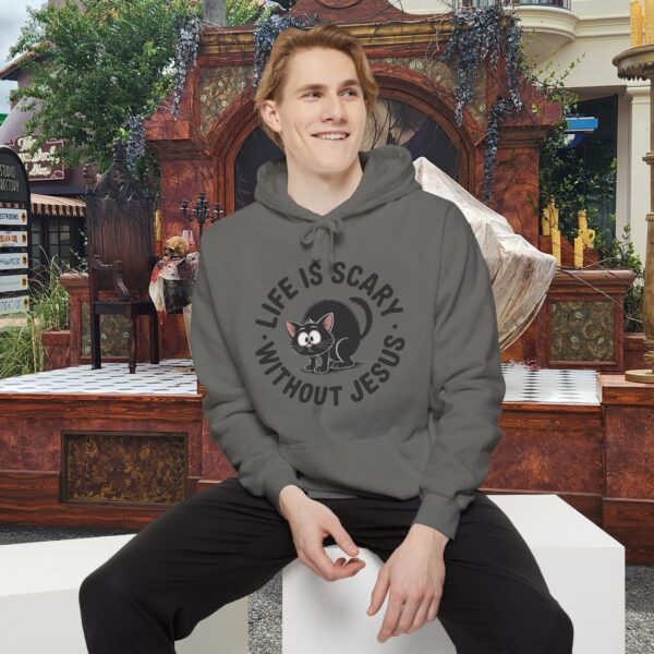 Model on a Halloween set wearing a gray Life is Scary Without Jesus Halloween Hoodie, design showing a cute frightened black cat.