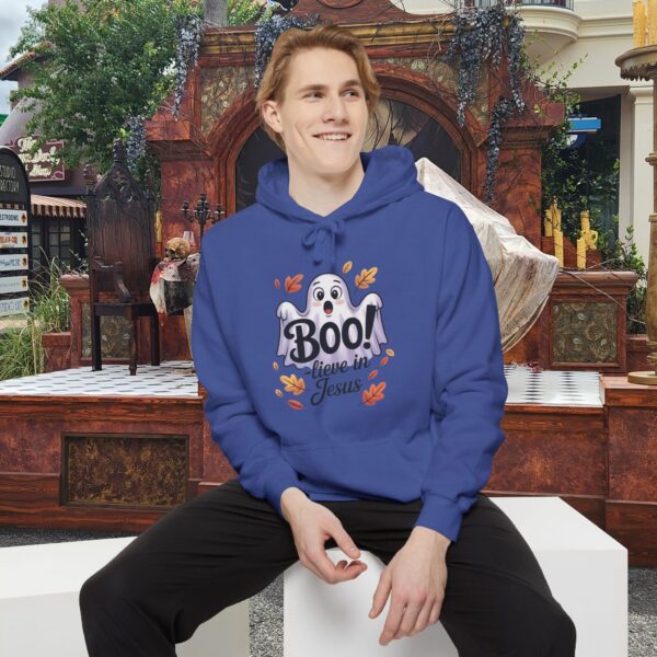 Model on a Halloween set wearing a Blue Boo! -lieve in Jesus Halloween Hoodie, design showing a cute ghost with fall leaves.