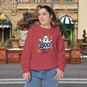 Model on a Halloween set wearing a Red Boo! -lieve in Jesus Halloween Sweatshirt, design showing a cute ghost with fall leaves.