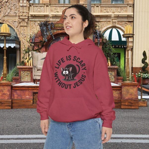 Model on a Halloween set wearing a red Life is Scary Without Jesus Halloween Hoodie, design showing a cute frightened black cat.